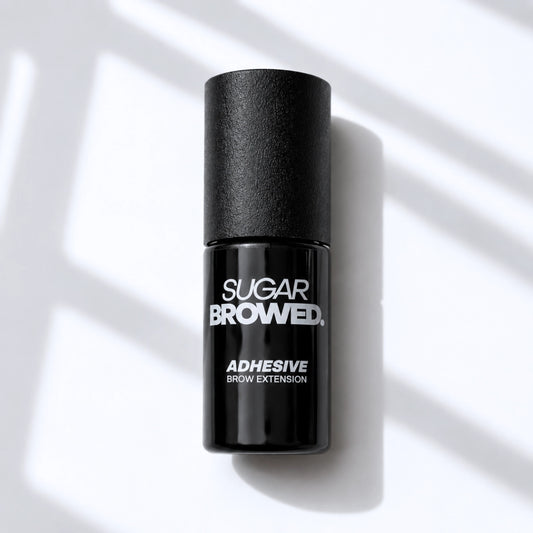 Black bottle of SUGAR BROWED. Adhesive for brow extensions on clean studio background – professional eyebrow glue for long-lasting results