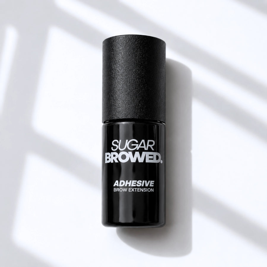 Black bottle of SUGAR BROWED. Adhesive for brow extensions on clean studio background – professional eyebrow glue for long-lasting results