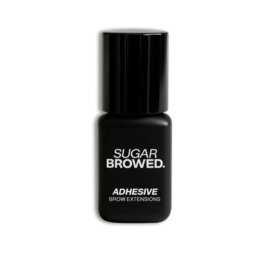 Black bottle of SUGAR BROWED. Adhesive for brow extensions on clean studio background – professional eyebrow glue for long-lasting results