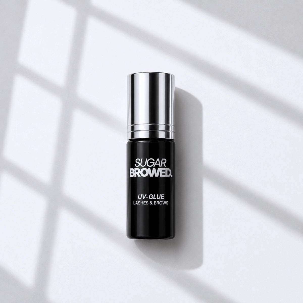High-resolution product image of SUGAR BROWED UV Glue for brow extensions, professional adhesive bottle with silver cap, showcased on a clean background.